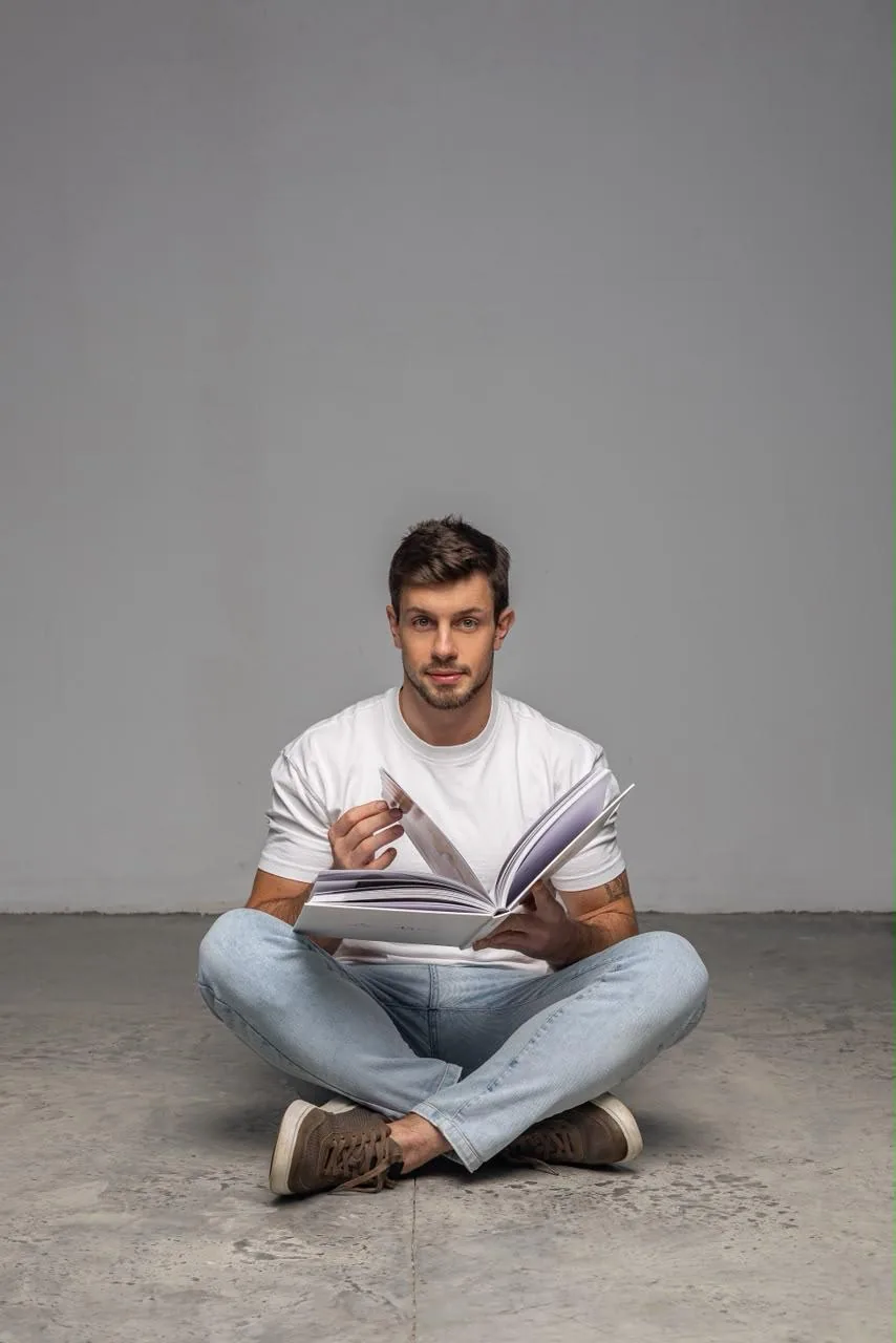 Davi Butzke sentado no chão, estudando com um livro aberto